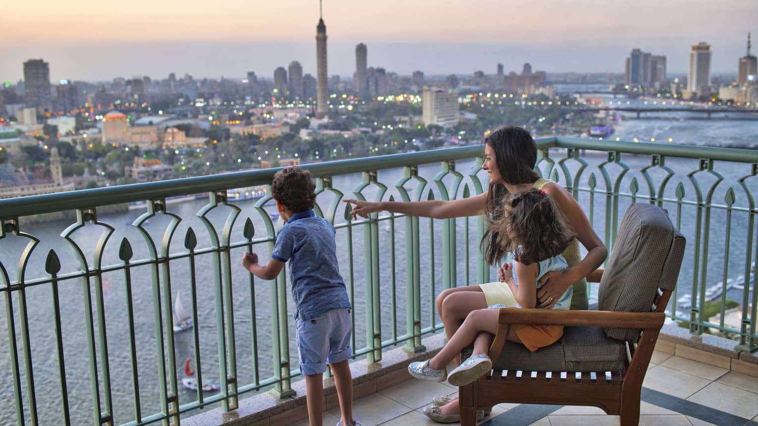 Woman seated with a young girl and beside a young boy standing, overlooking the Nile River and Cairo