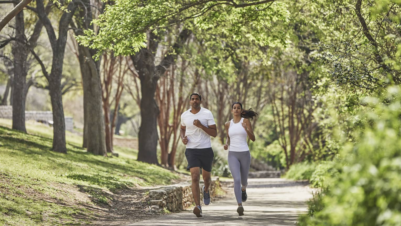 Two guests run together along a tree-lined path