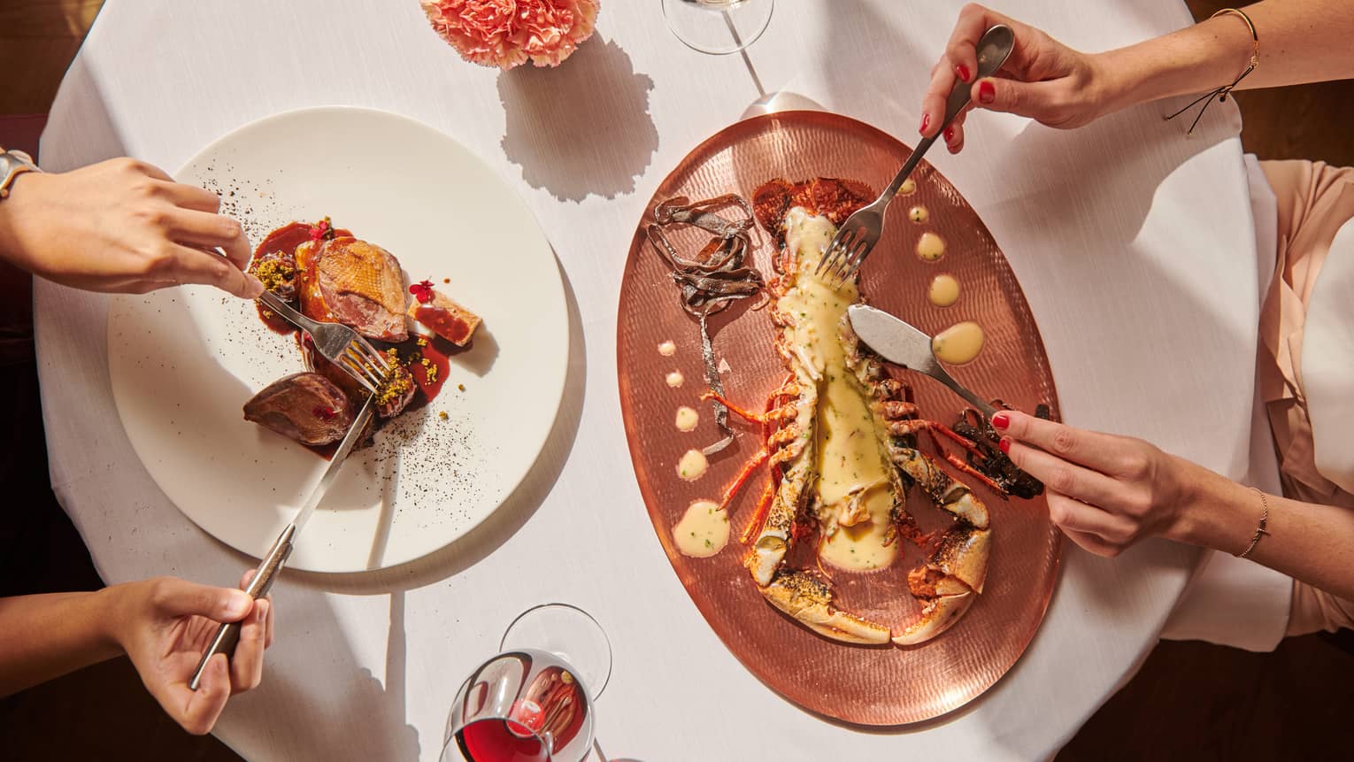 Two people enjoying a gourmet meal at a restaurant. The scene conveys an atmosphere of fine dining and culinary indulgence.