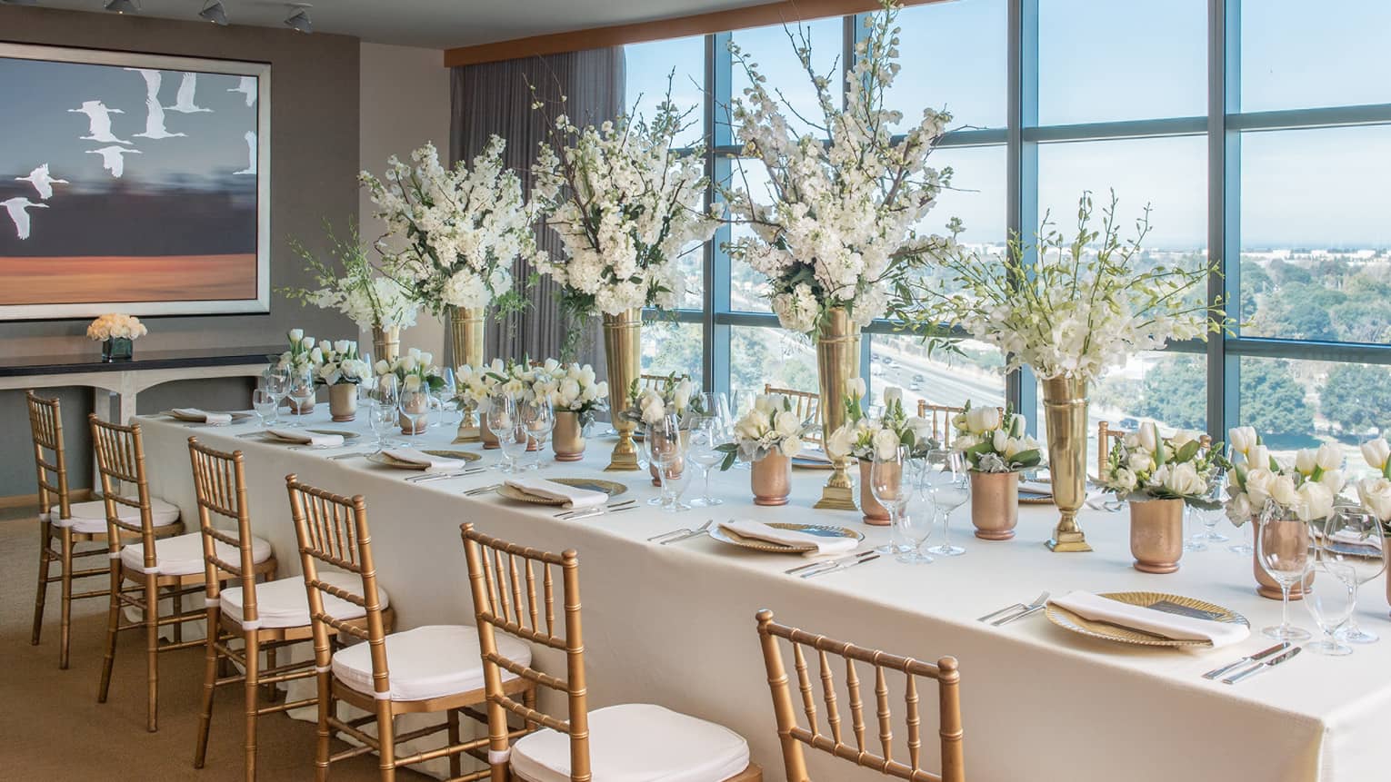 Sky Suite long dining table with white linens, flower centrepieces by window overlooking Palo Alto