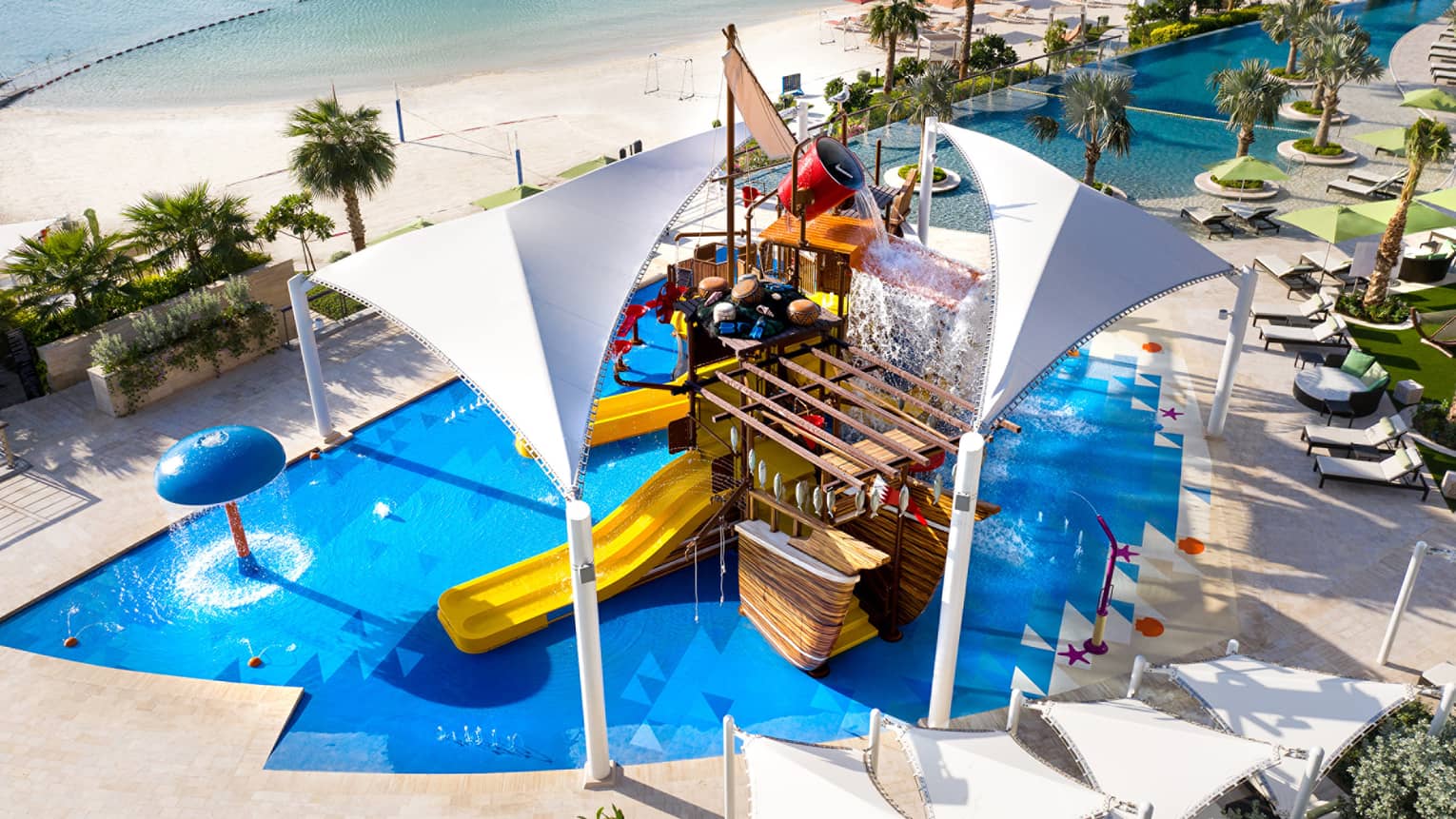 A large orange waterslide built into a faux pirate ship descending into a crystal blue pool of water.