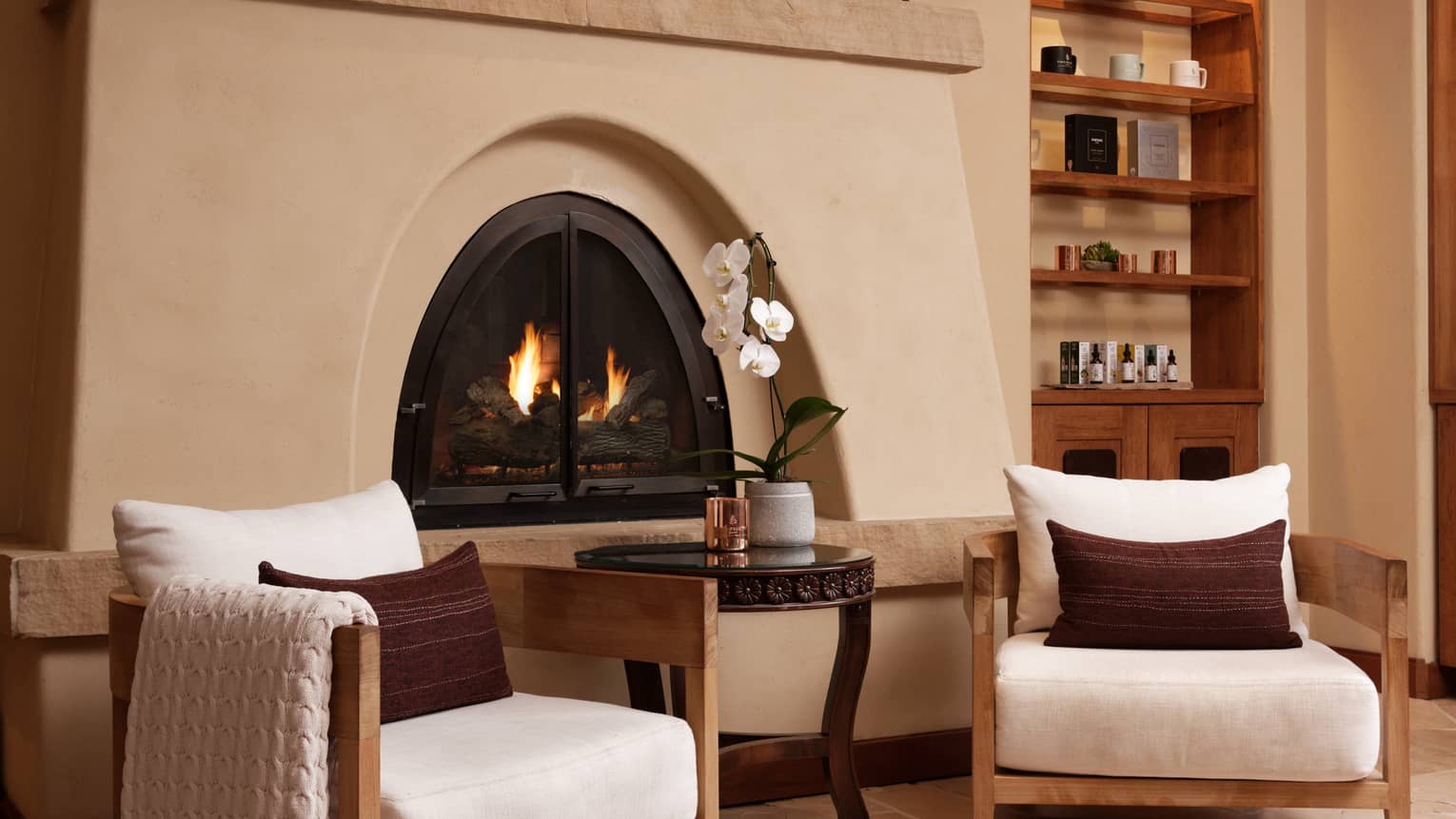 A sitting area with a fireplace, chairs and a small table.