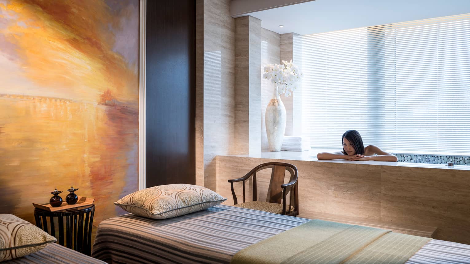Woman rests head, arms on Spa tub beside massage table