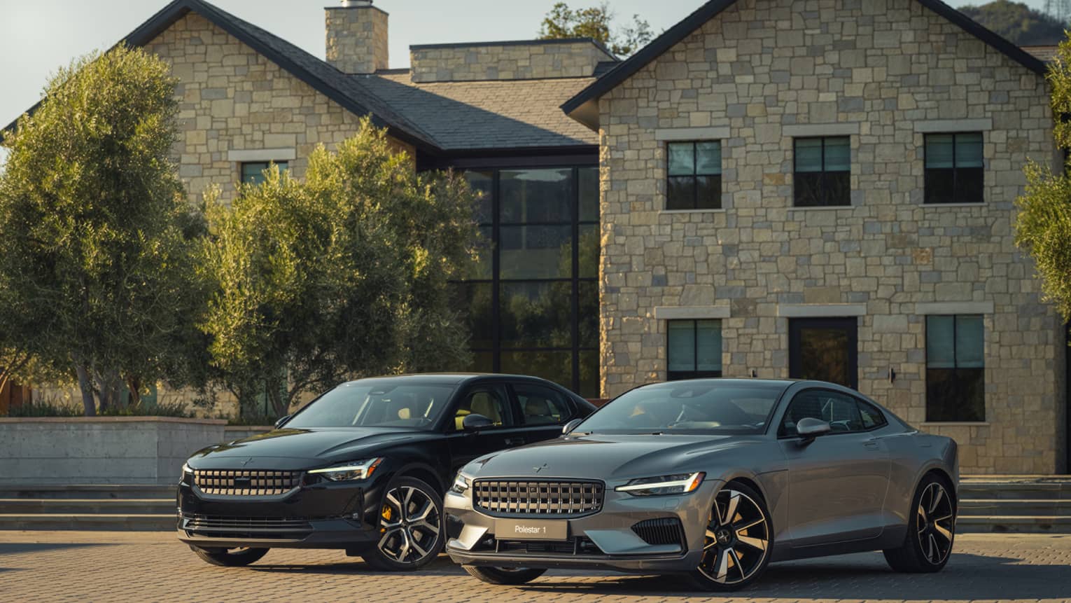 Two cars in front of a large stone and brick building.