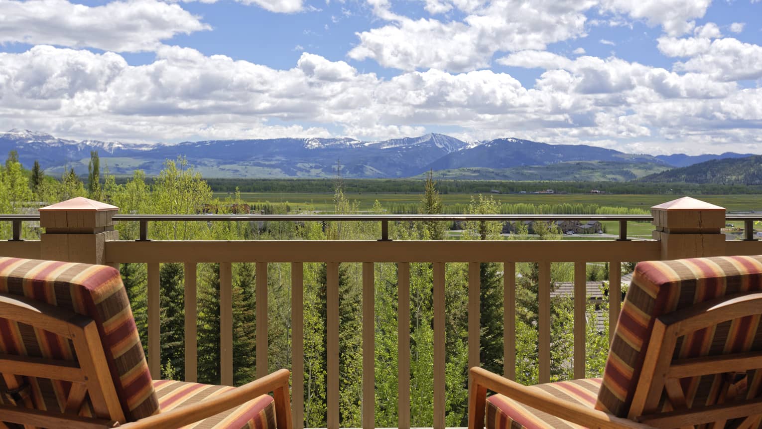 Two chairs on outdoor wooden deck looking out to lush mountain valley