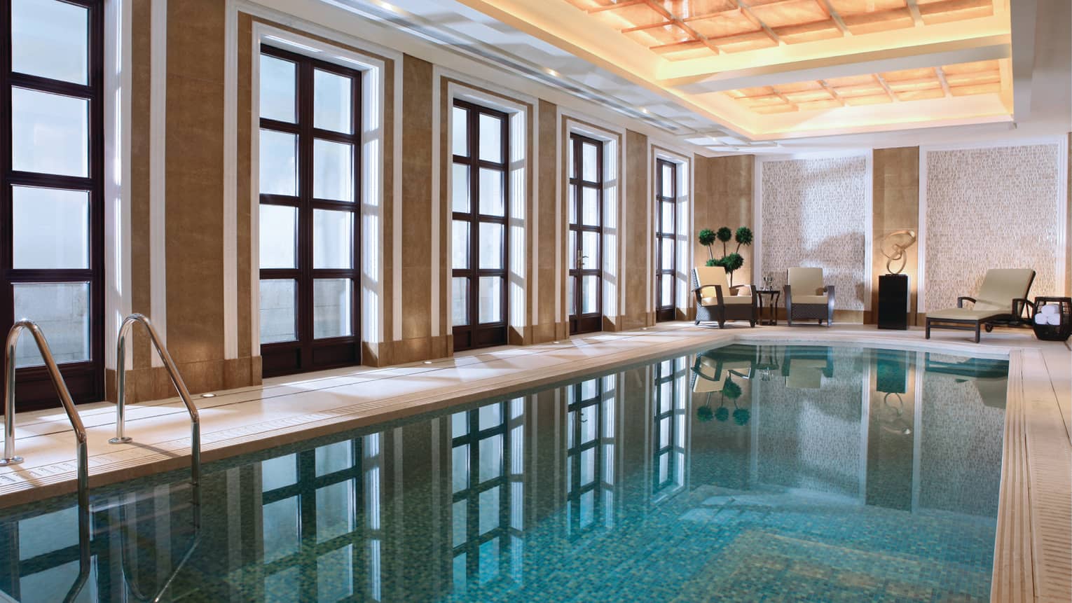 Floor-to-ceiling windows reflecting on long indoor swimming pool