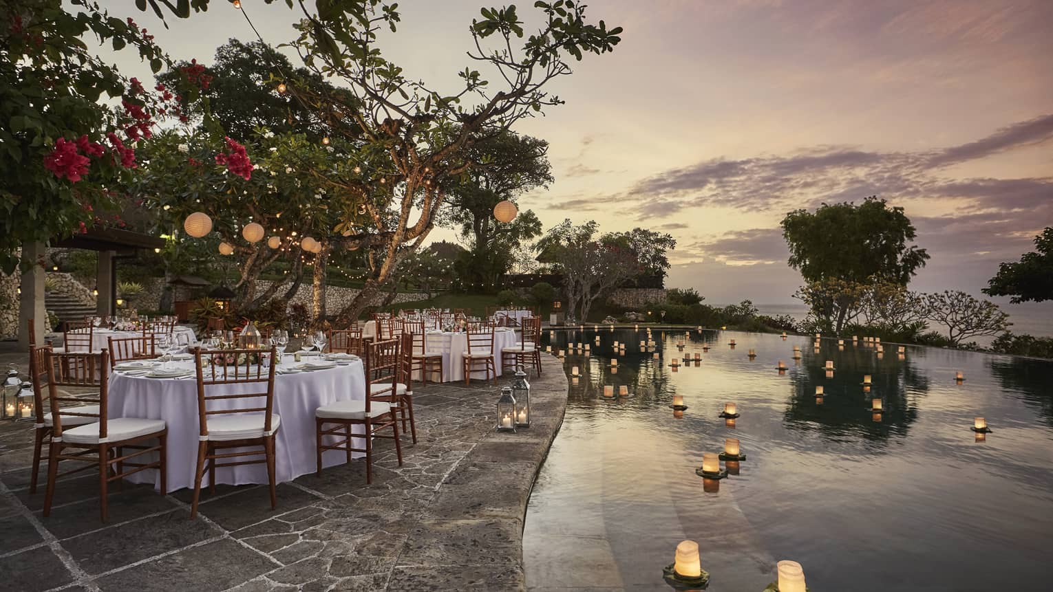 Pool Terrace banquet dining tables by candles floating on water at sunset