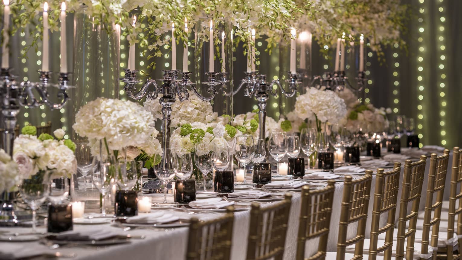 Elaborate white flowers and candelabras serve as the centerpiece of a dining arrangement