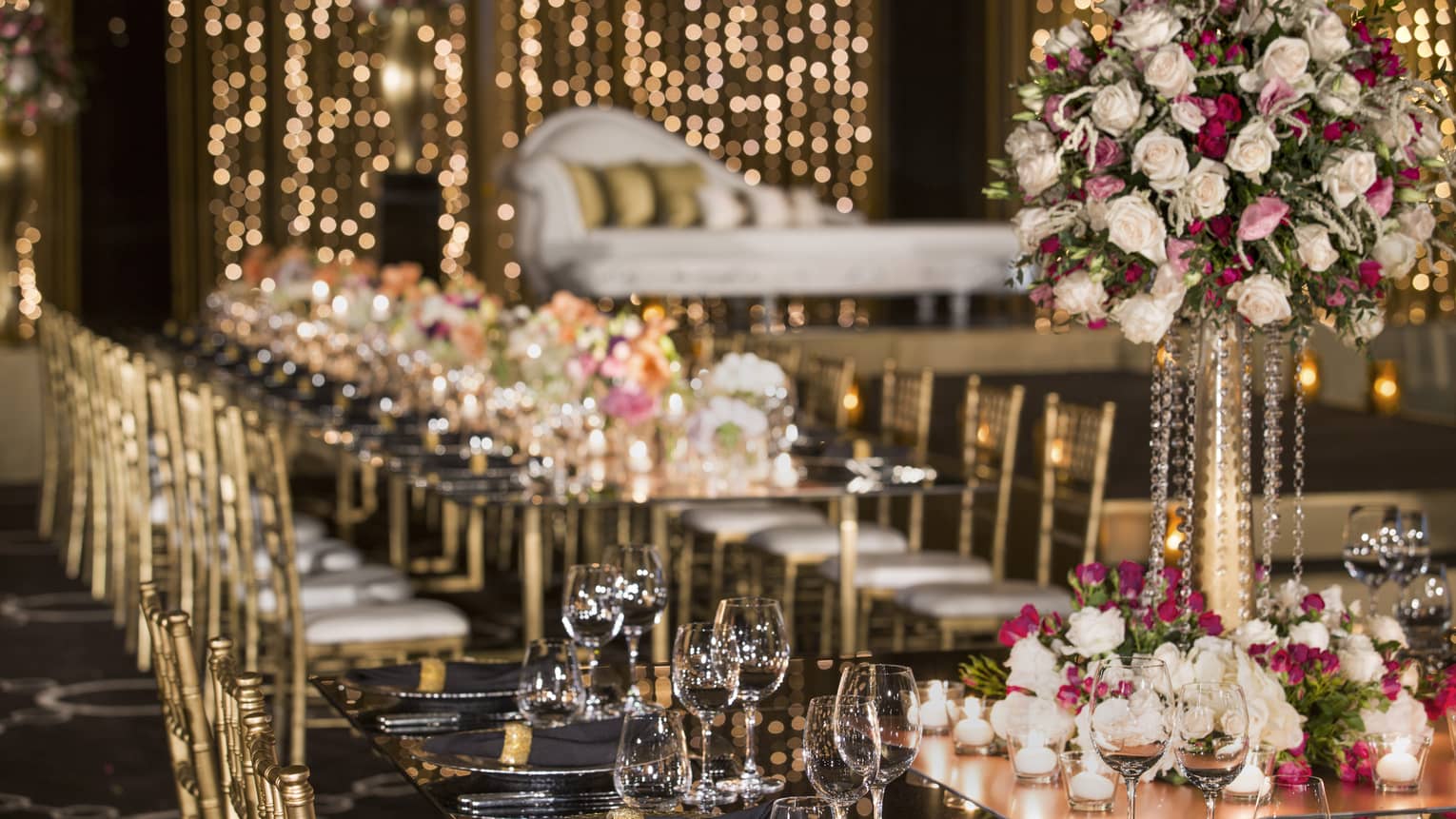 Wine glasses, roses on wedding banquet table before elegant chaise lounge chair 