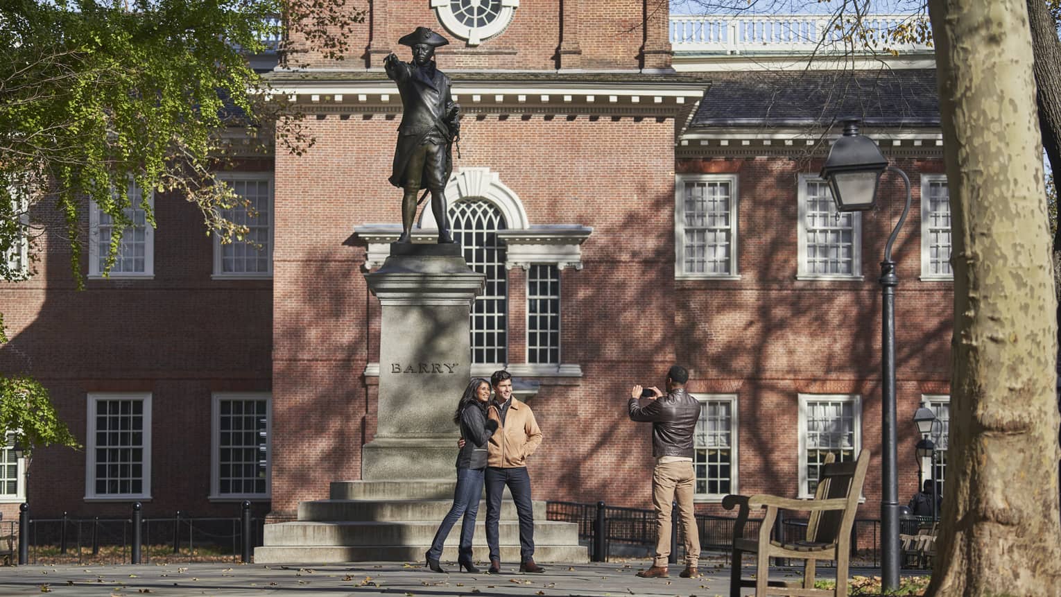 Couple poses for photo in front of statue and historic building