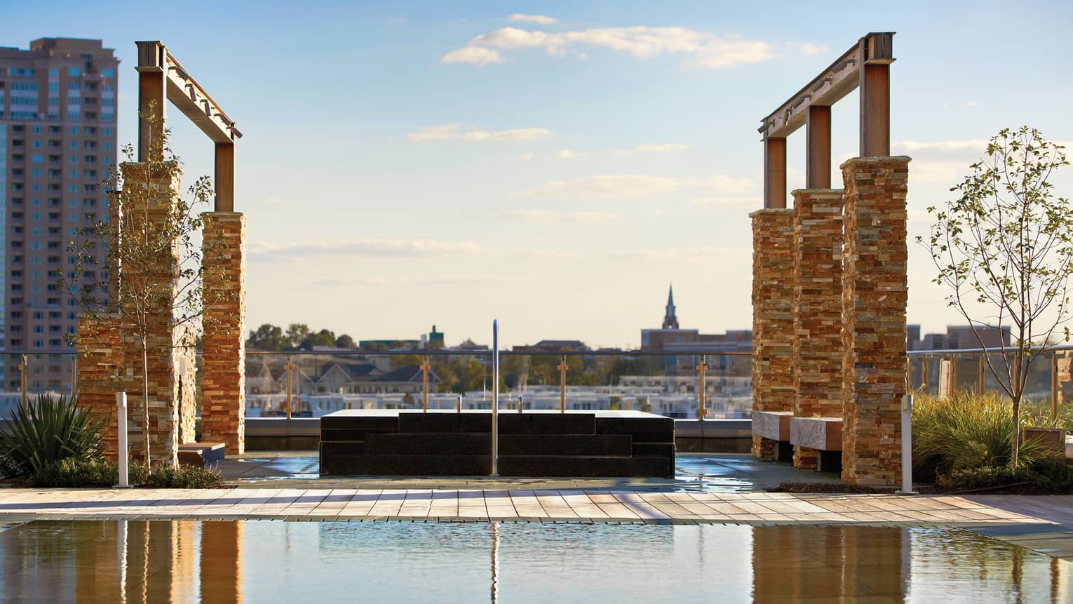 Tall brick pillars, frames over outdoor rooftop whirlpool and reflecting pool