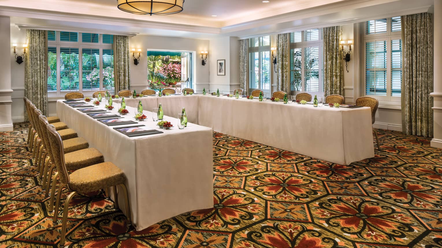 El Jardin carpeted meeting room with modular tables set with water bottles, fresh grapes