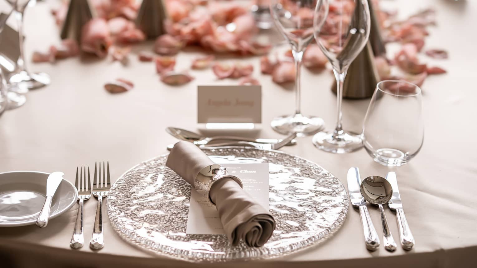 Wedding place setting with name card and pink rose petals