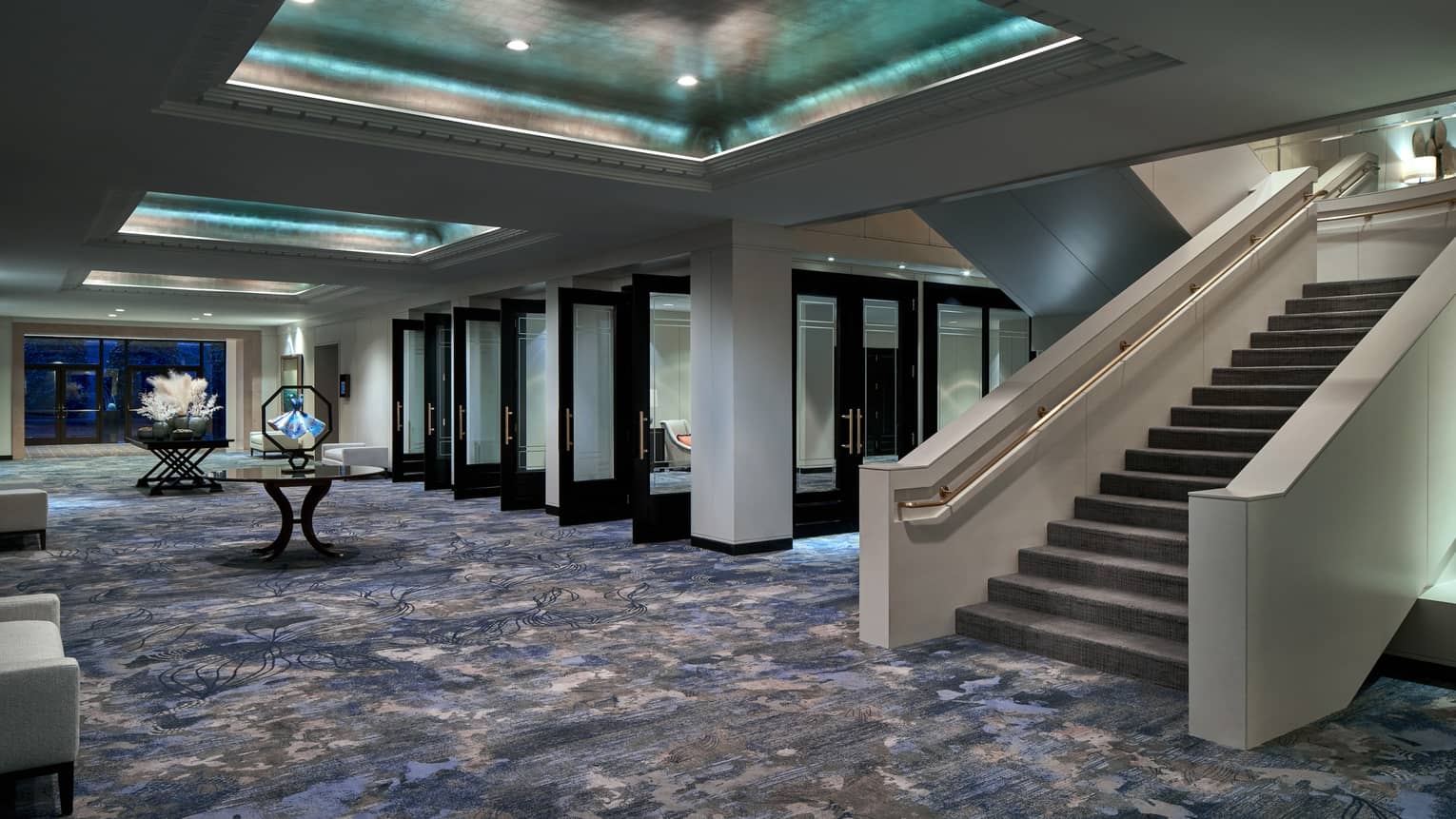 Events hall with blue-ish carpeting, grand staircase and inset metallic ceiling with recessed lights