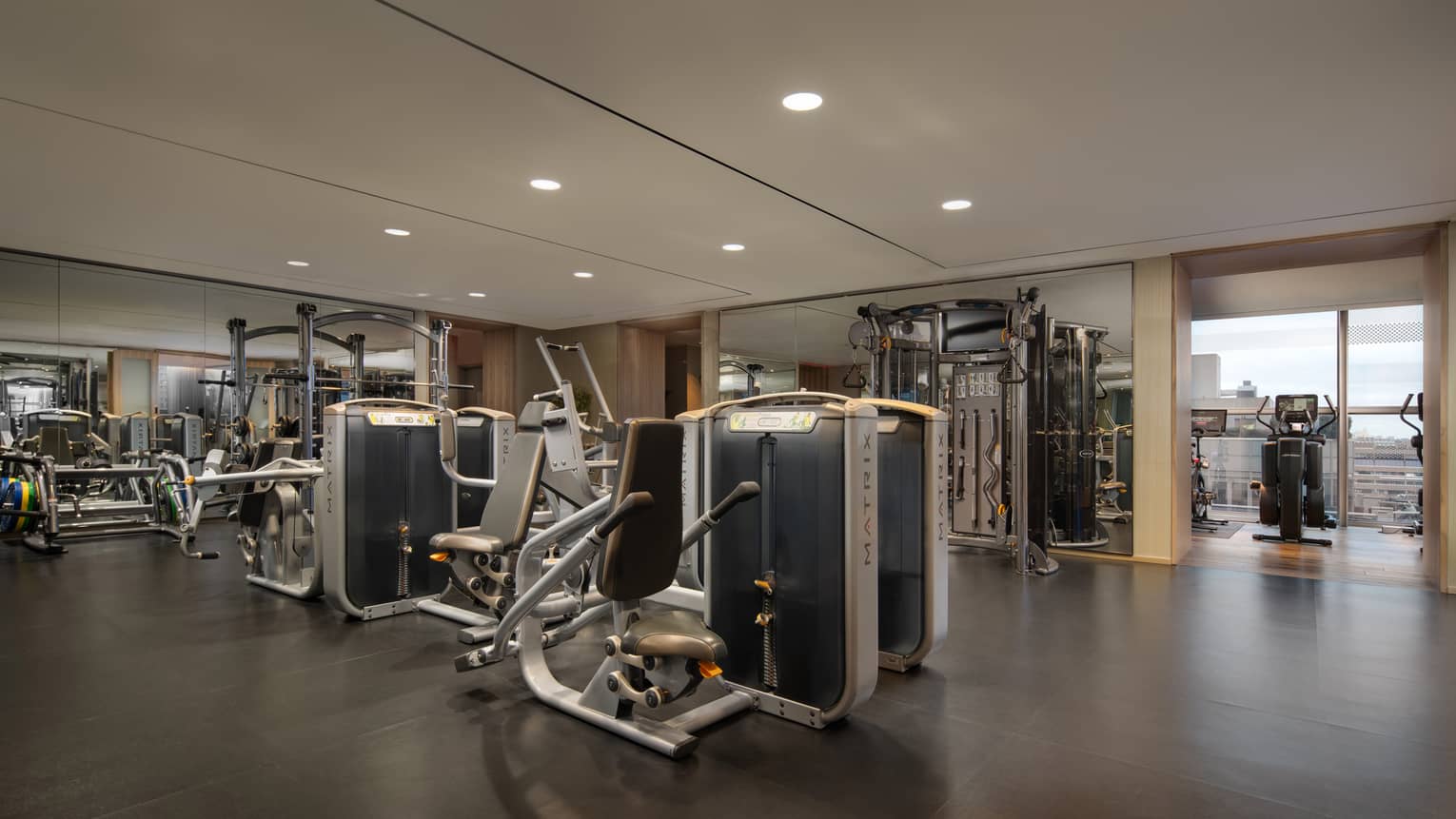 Fitness centre with assorted equipment and floor-to-ceiling windows with city views