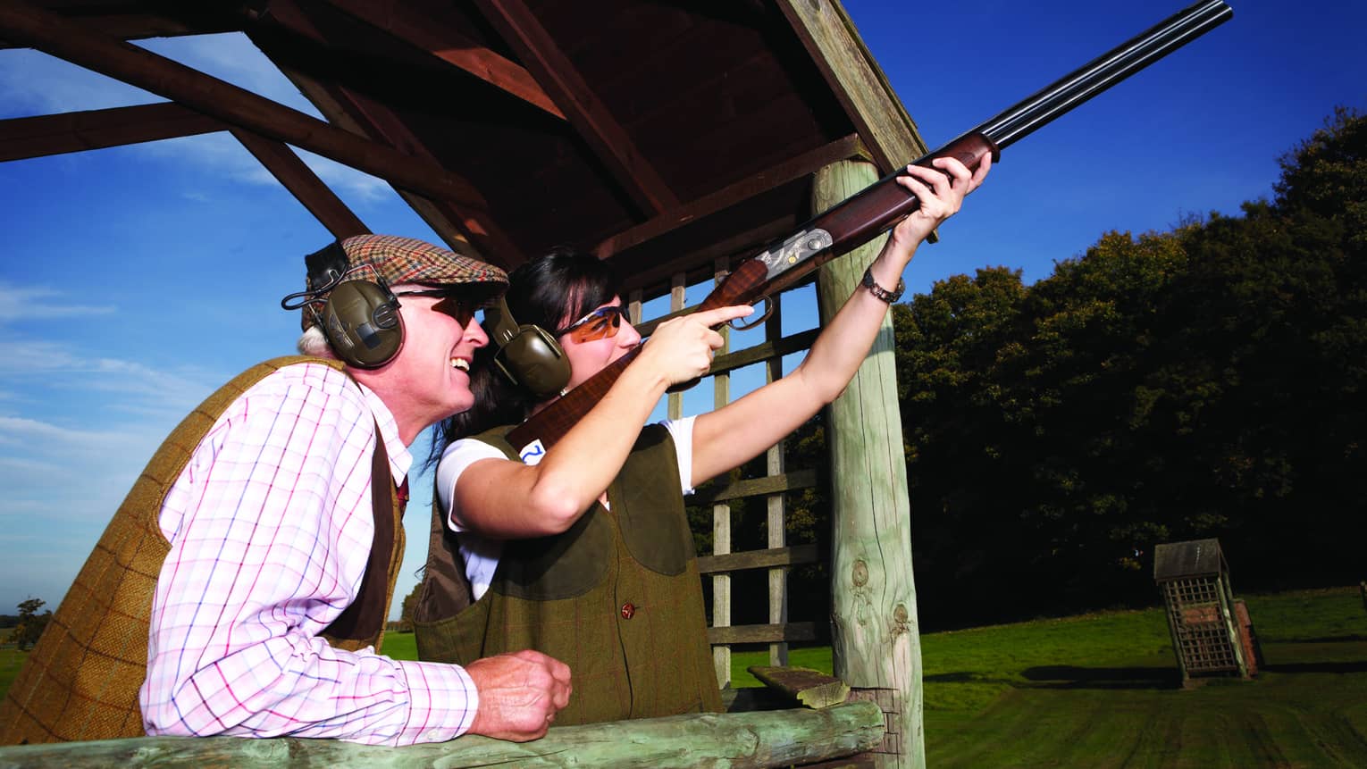A man and woman shooting clay pigeons outside