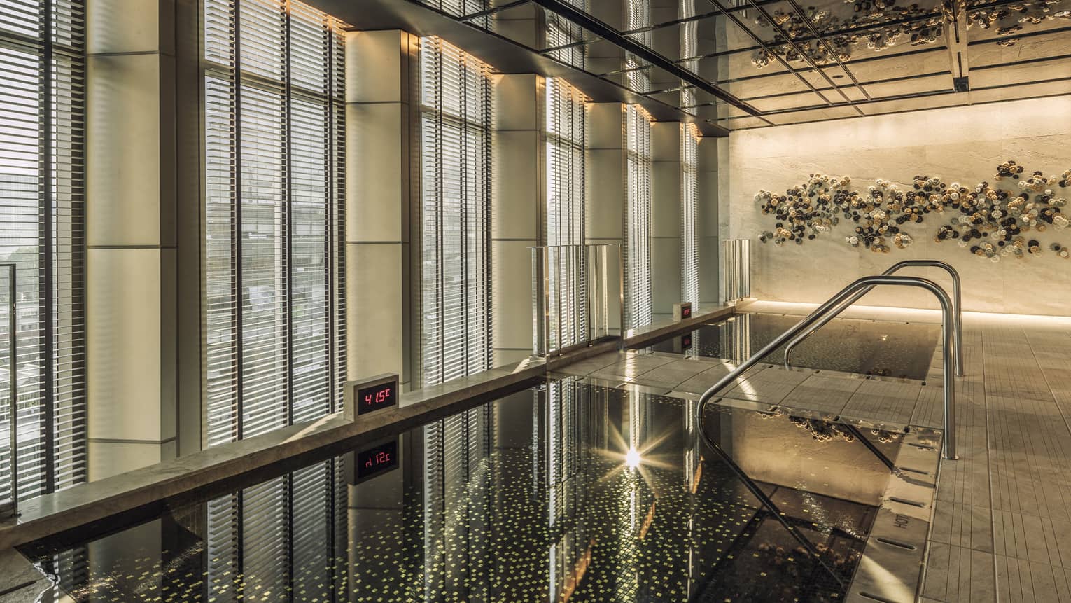 Korean Sauna windows with blinds over two mosaic tile pools reflecting sparkling lights