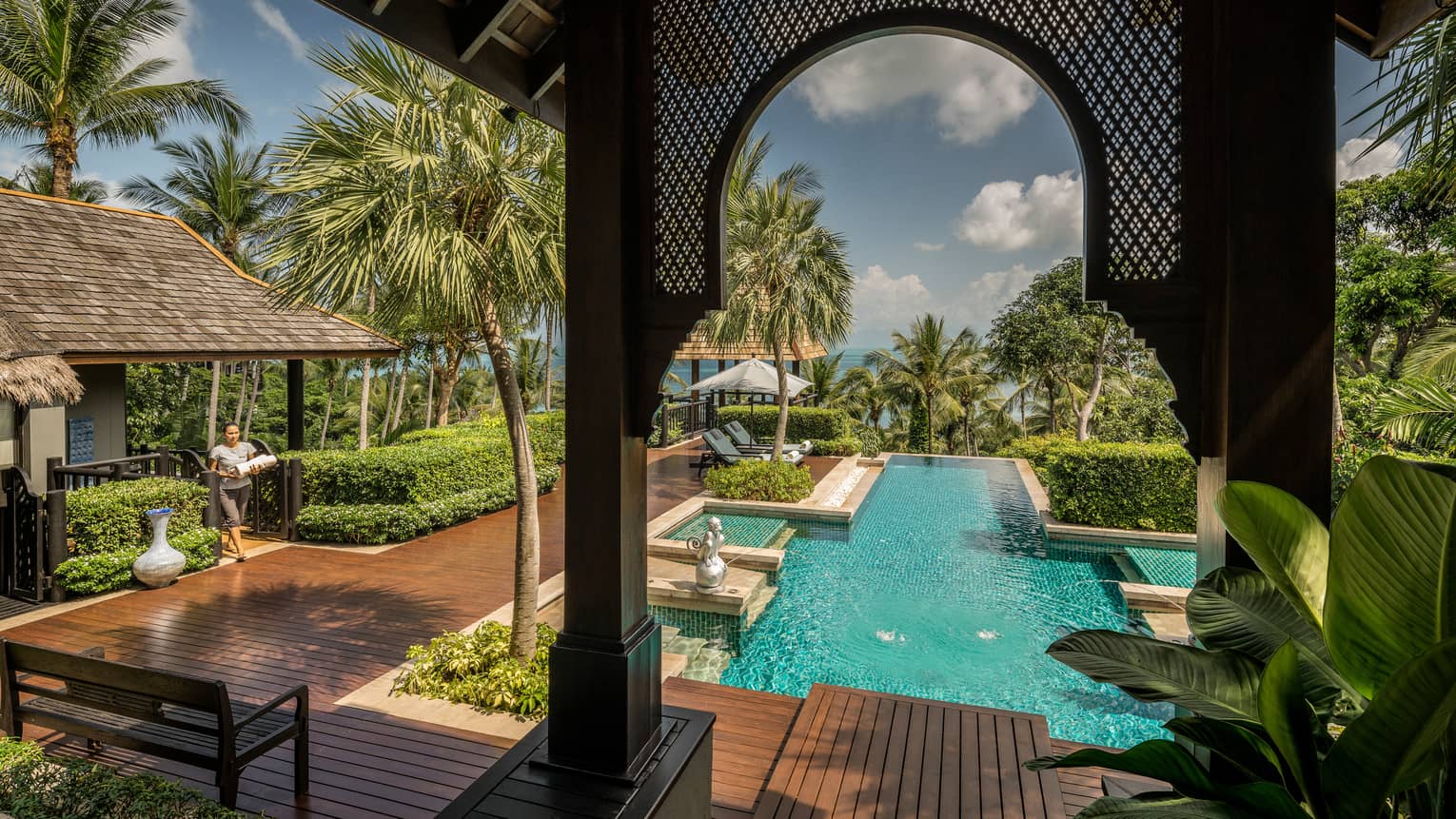 View from arched pergola to long outdoor swimming pool, sunny deck