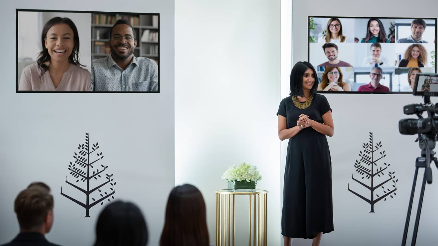 Several people host a virtual meeting in a room with the Four Seasons logo.