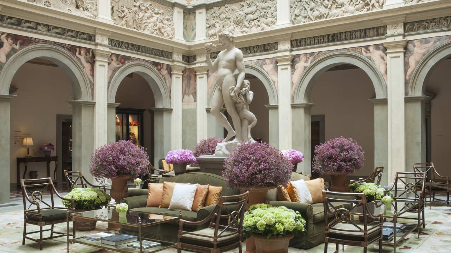 Il Palazzo lobby, sunny atrium with stone statue on pedestal over seating area, purple flowers 