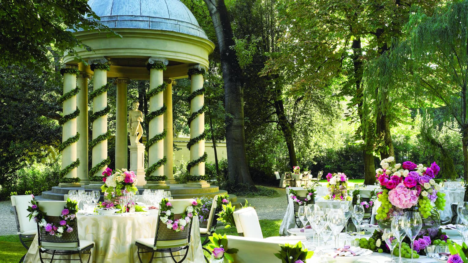 Garden reception, round, flower covered banquet tables by gazebo with white pillars