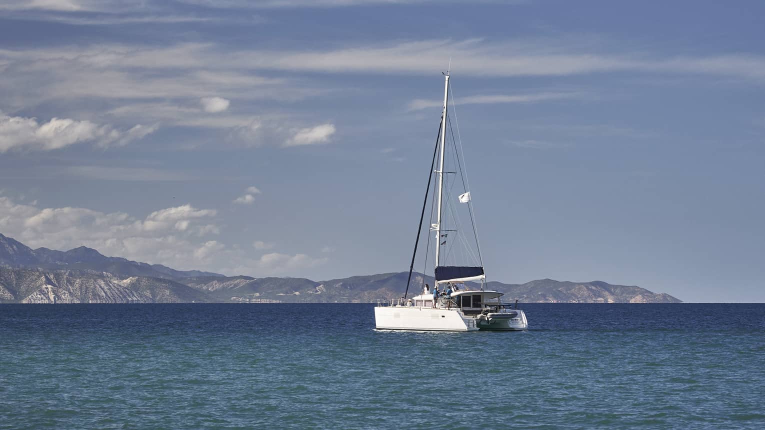 A boat sailing on the ocean with mountains in the distance.