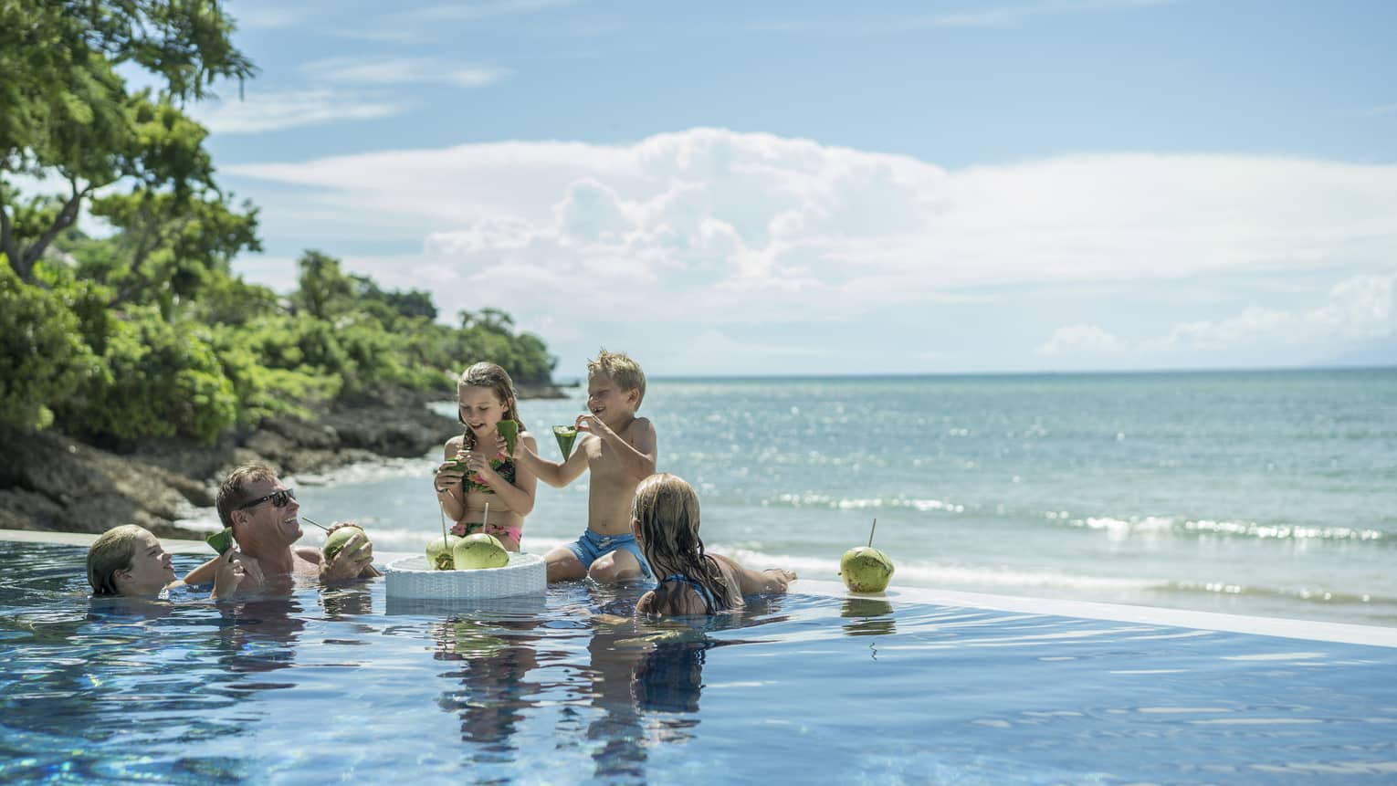 A family enjoying fresh coconuts outside in the Sundara pool