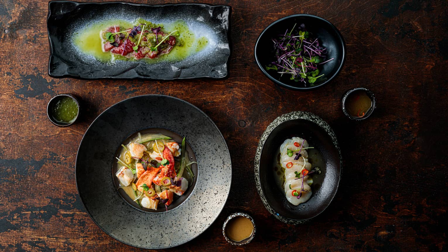 Several black plates filled with various asian cuisine.