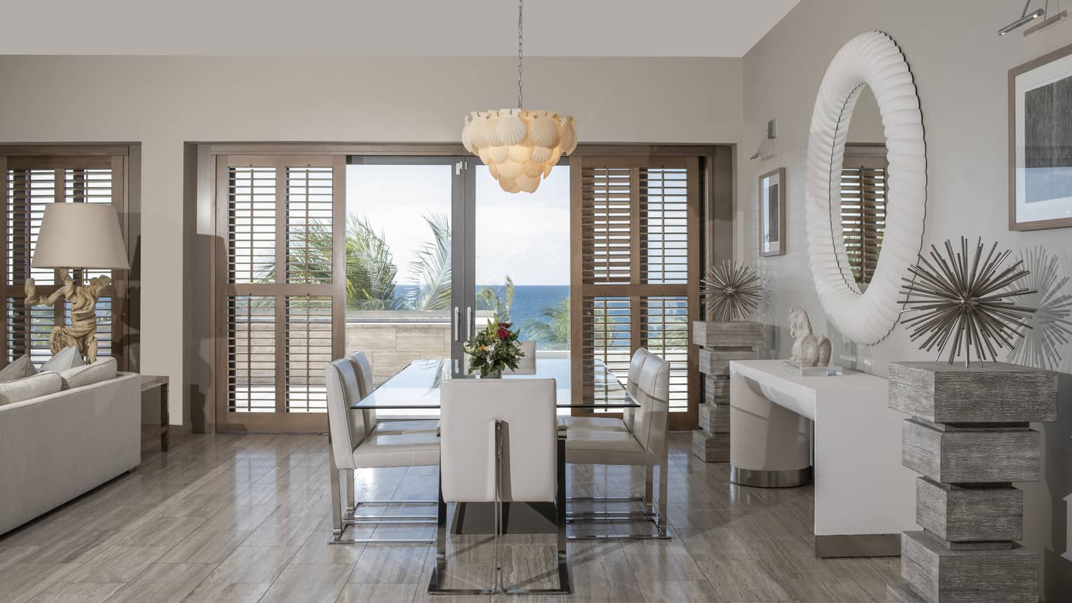 Dining room with grey wooden floors, light grey furniture, walk-out terrace with sea view