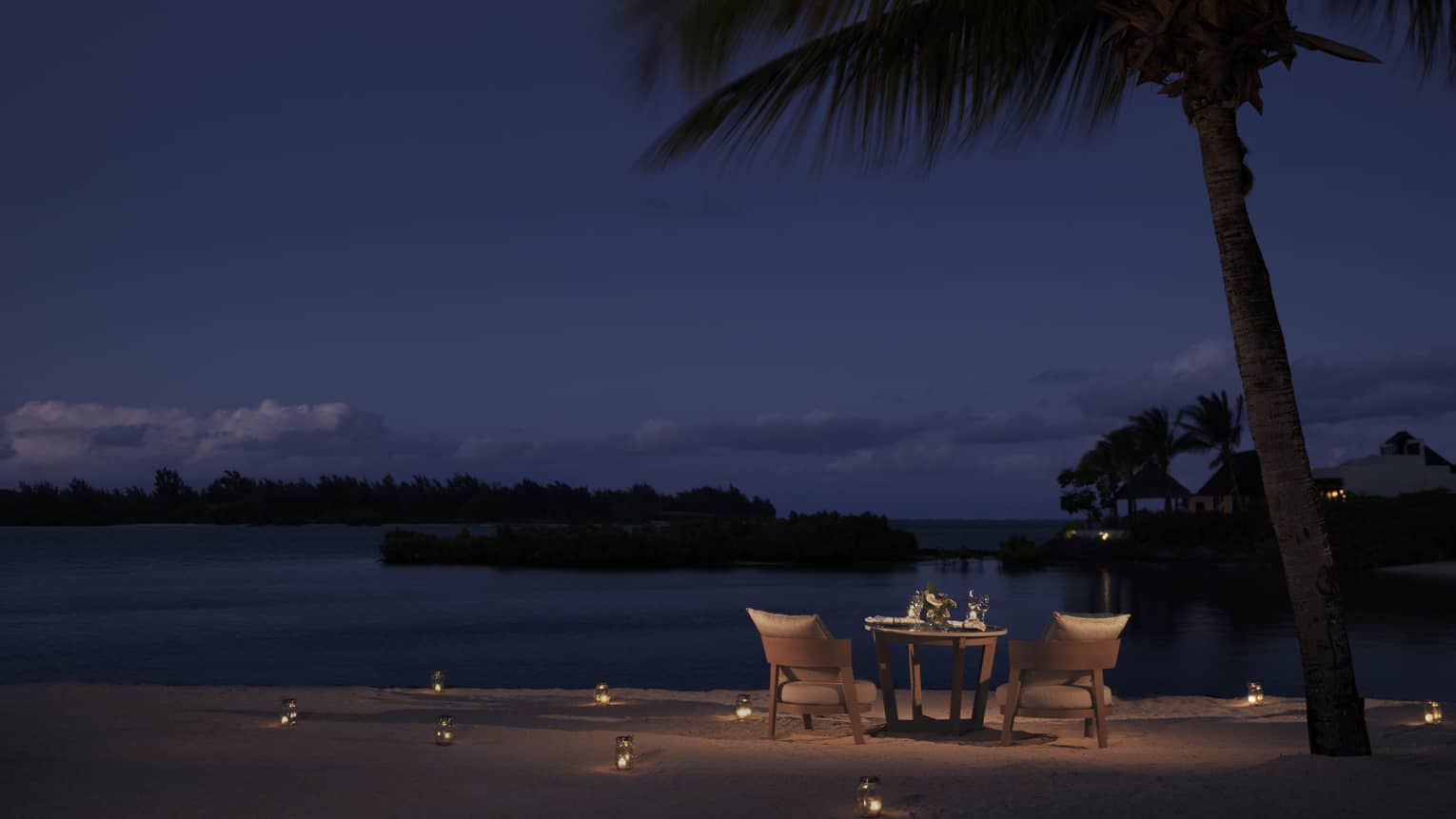 Dining table on beach, candles in sand, under starry night sky