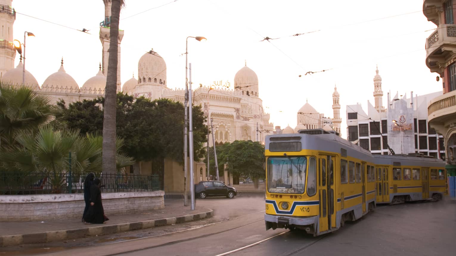 Yellow trolley car on track in front of El-Mursi Abul Abbas Mosque on sunny day