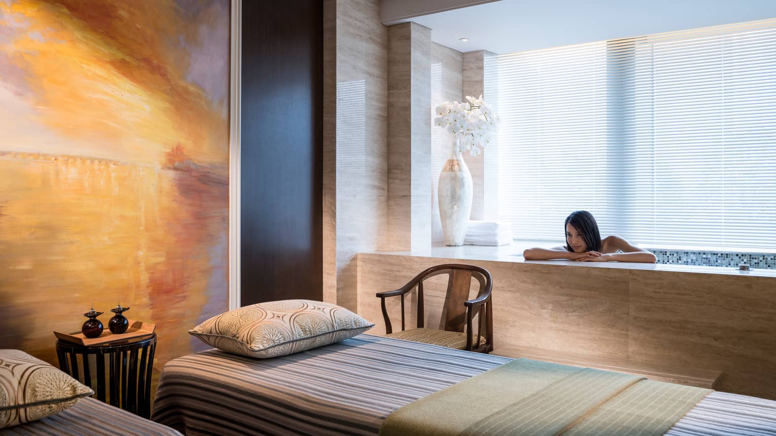 Woman rests head, arms on Spa tub beside massage table