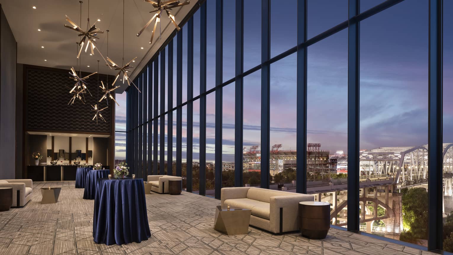 Indoor pre-function space with a wall of windows looking out to Nashville at dusk