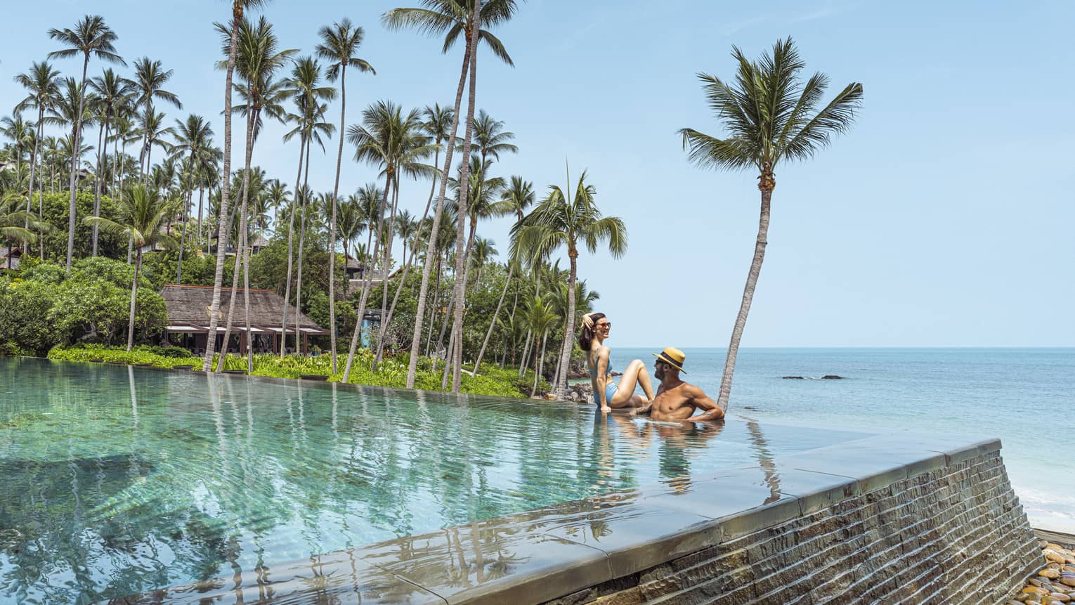 Couples relaxes in beachfront infinity-edge pool