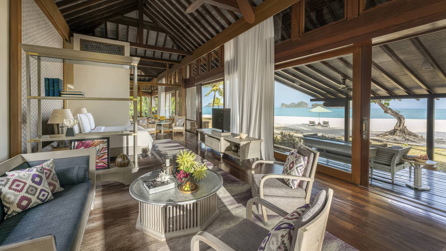 Teak living room opening to covered terrace with beach view