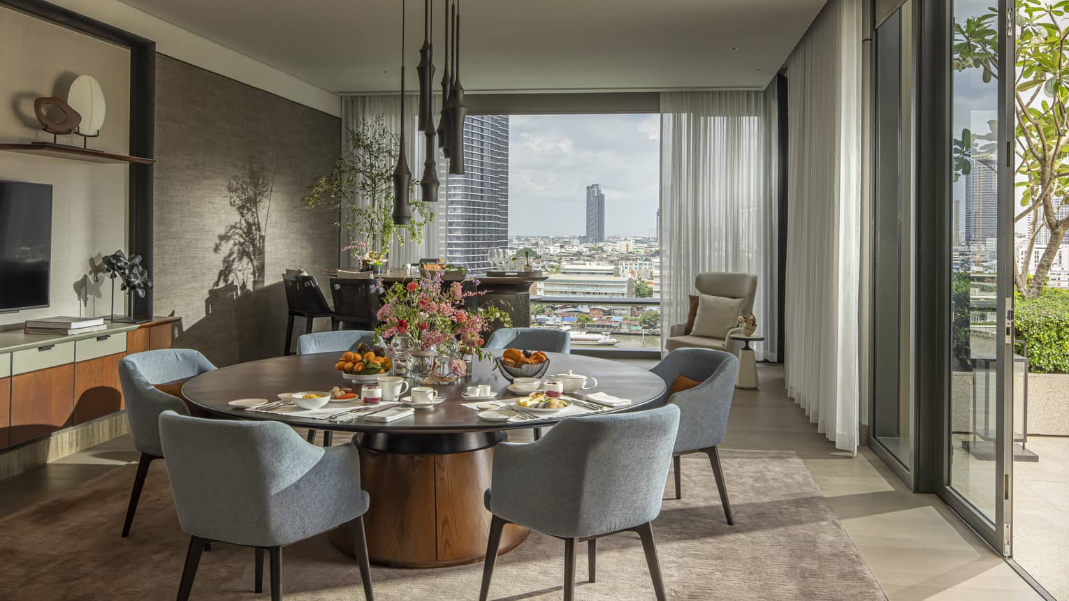 Hotel suite with large round dining table and views of Bangkok