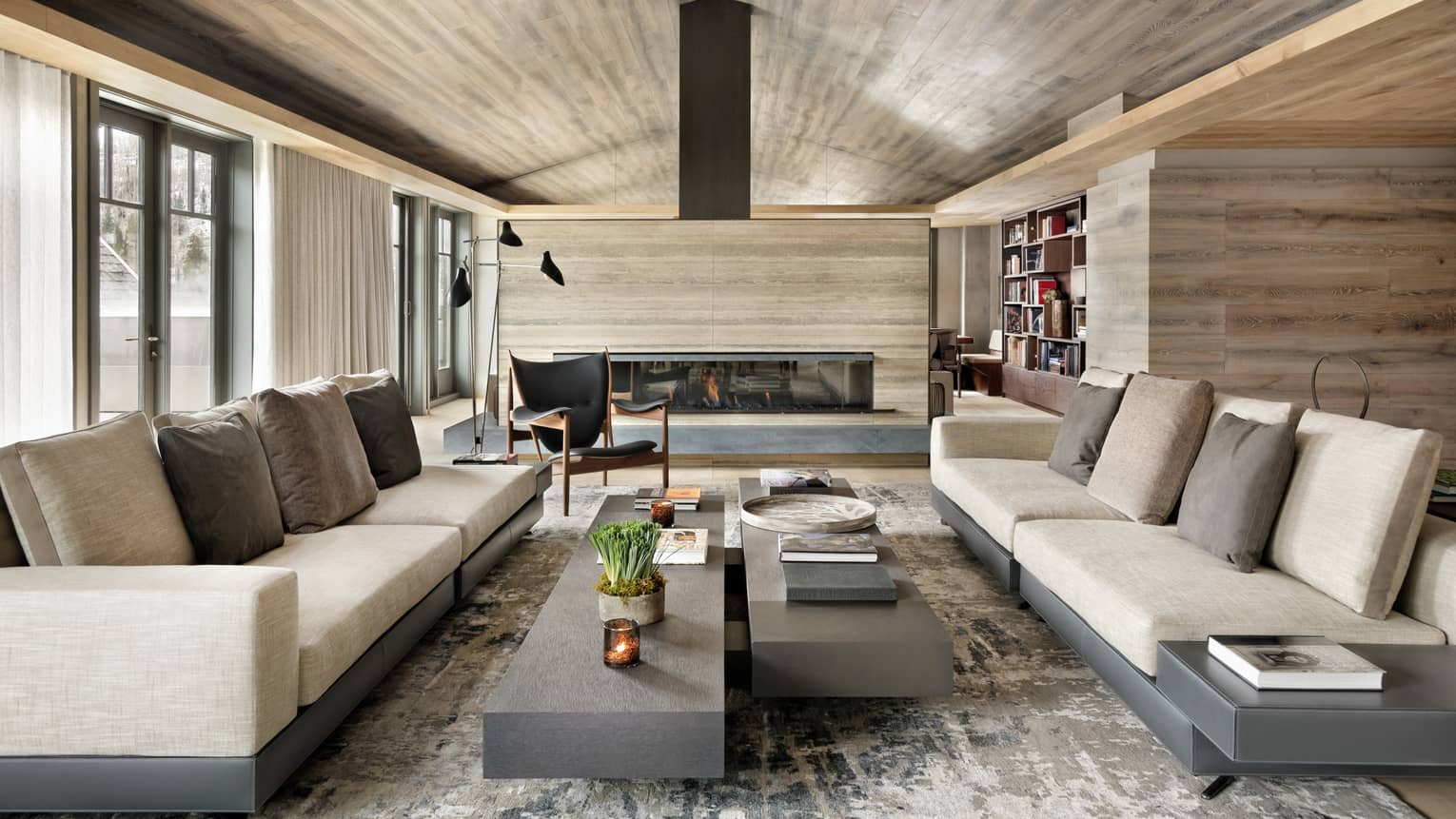Long linen sofas, slate coffee tables under modern light wood ceiling, fireplace