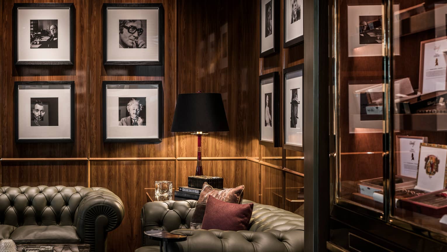 Churchill Club lounge two leather sofas against dark wood wall, framed black-and-white photos on walls