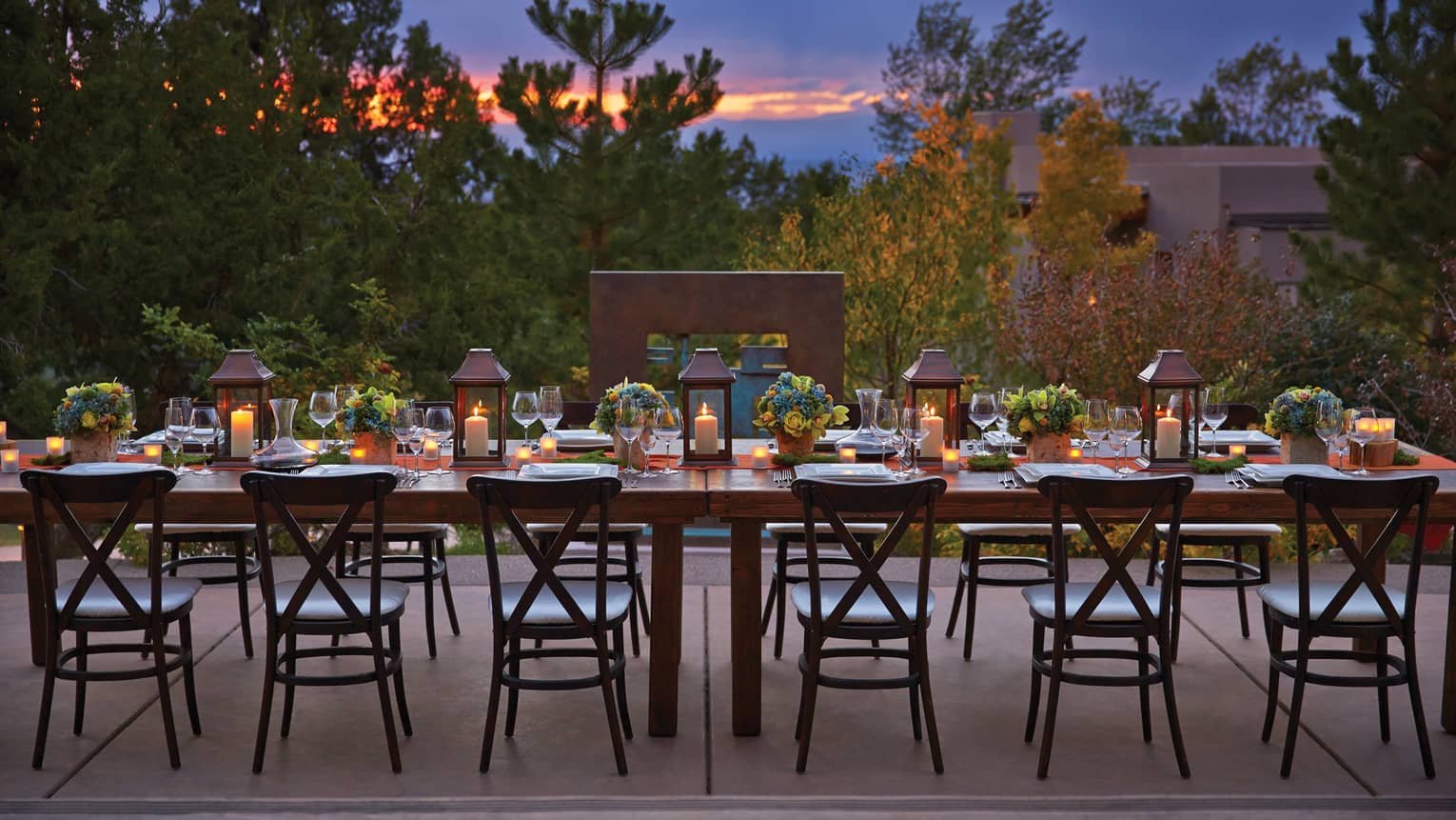 Long, candle-lit dining table on Terra patio at sunset