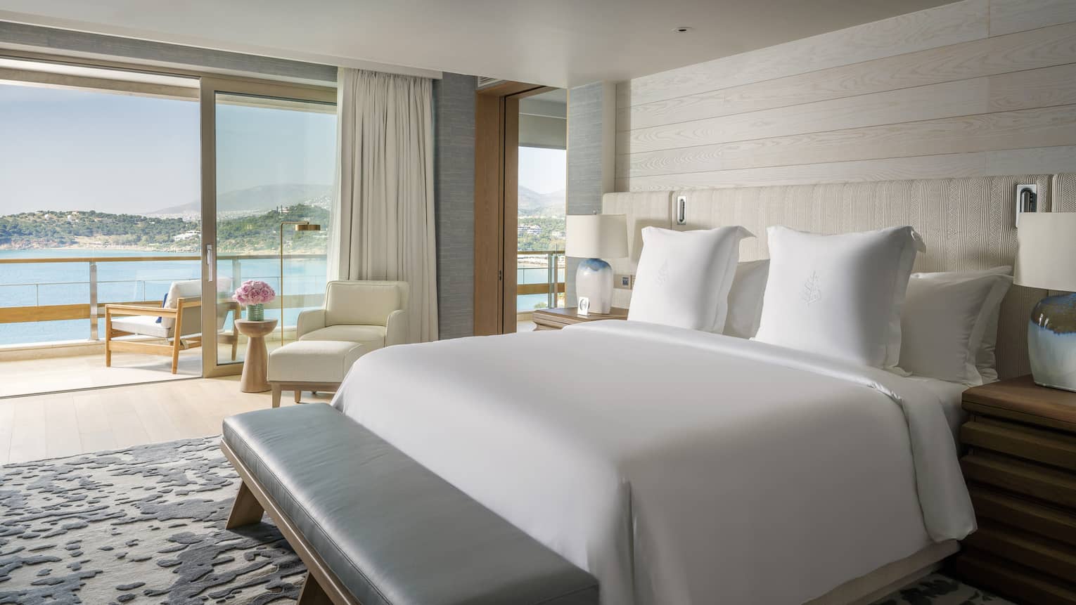 Arion Sea View Suite with white bedding, balcony with chairs overlooking ocean