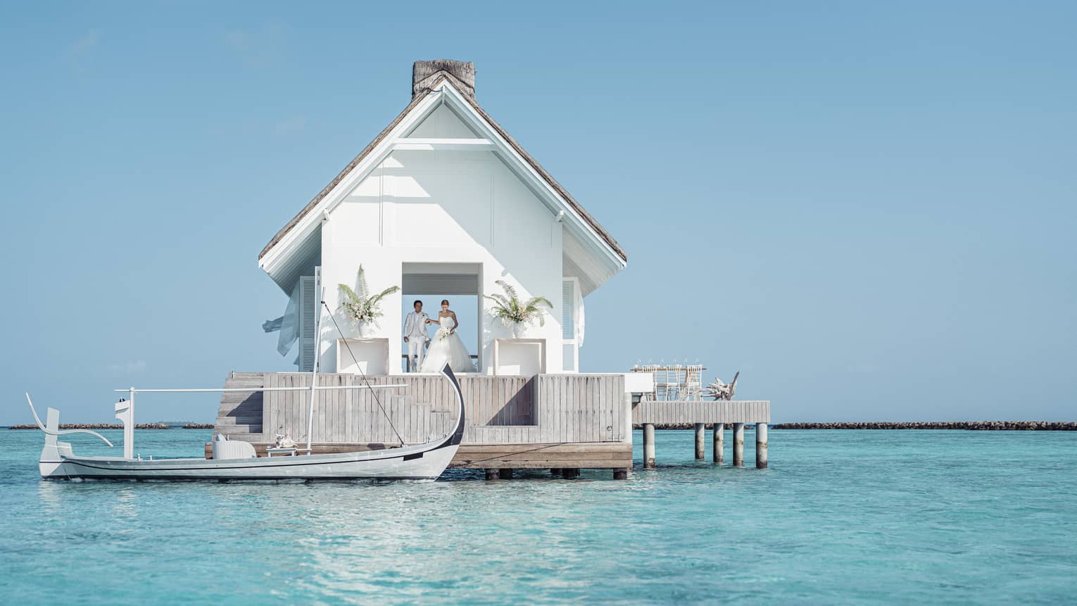 Bride and groom emerge from their overwater wedding pavilion