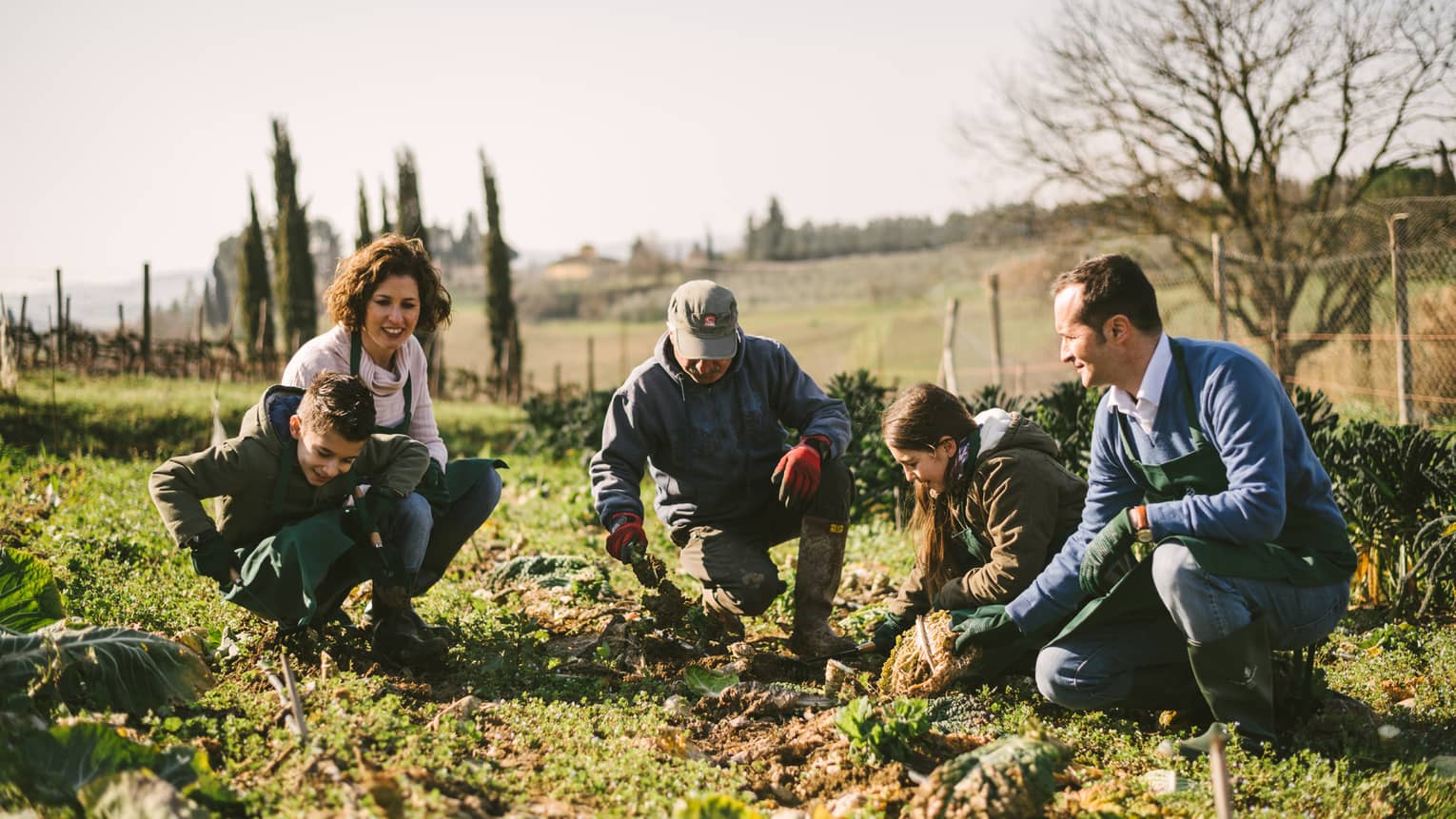 Smiling family helps farmer in the garden at Fattoria San Michele farm