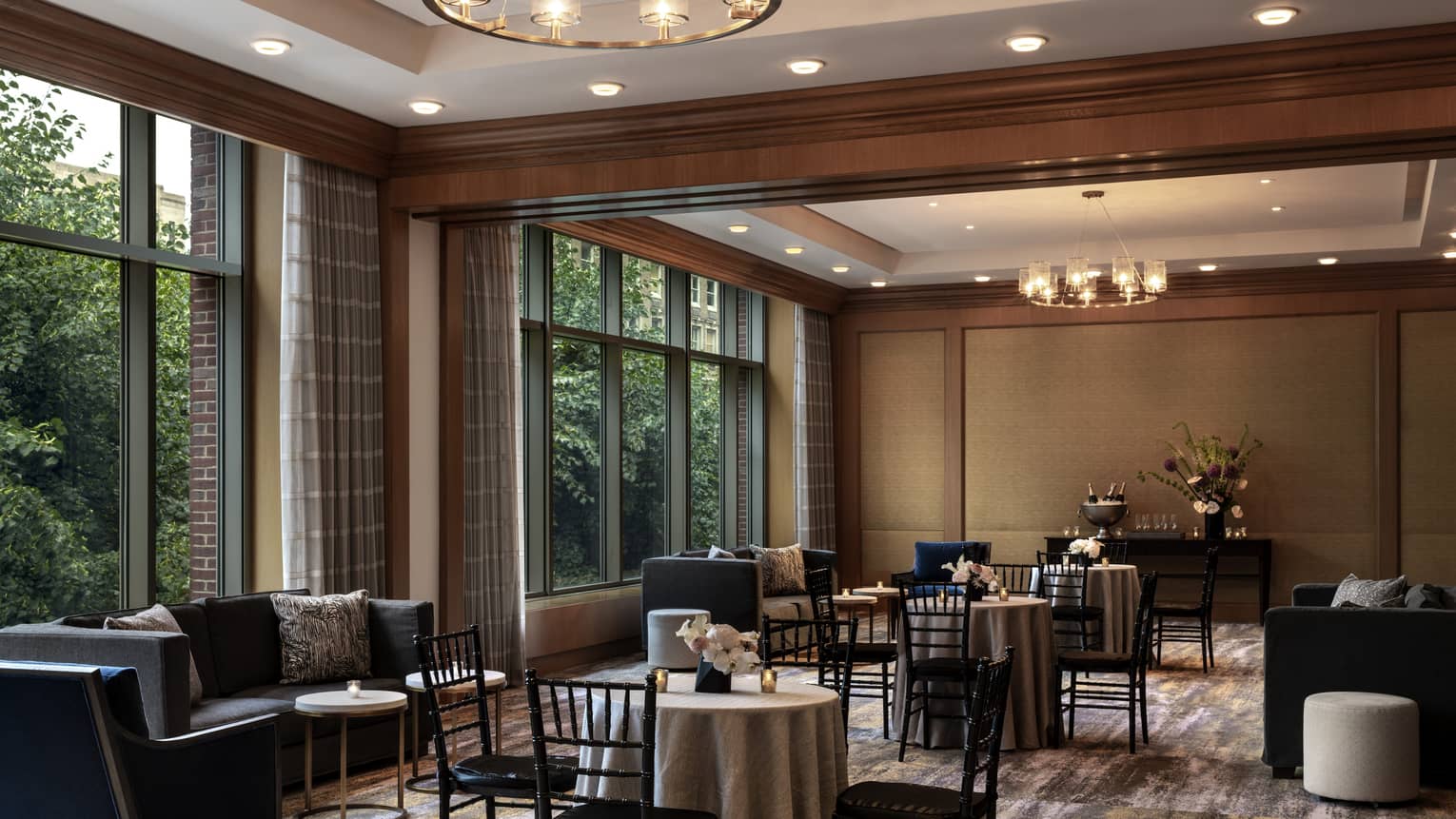 A  dimly lit seating area with black chairs around small tables and small black sofas.