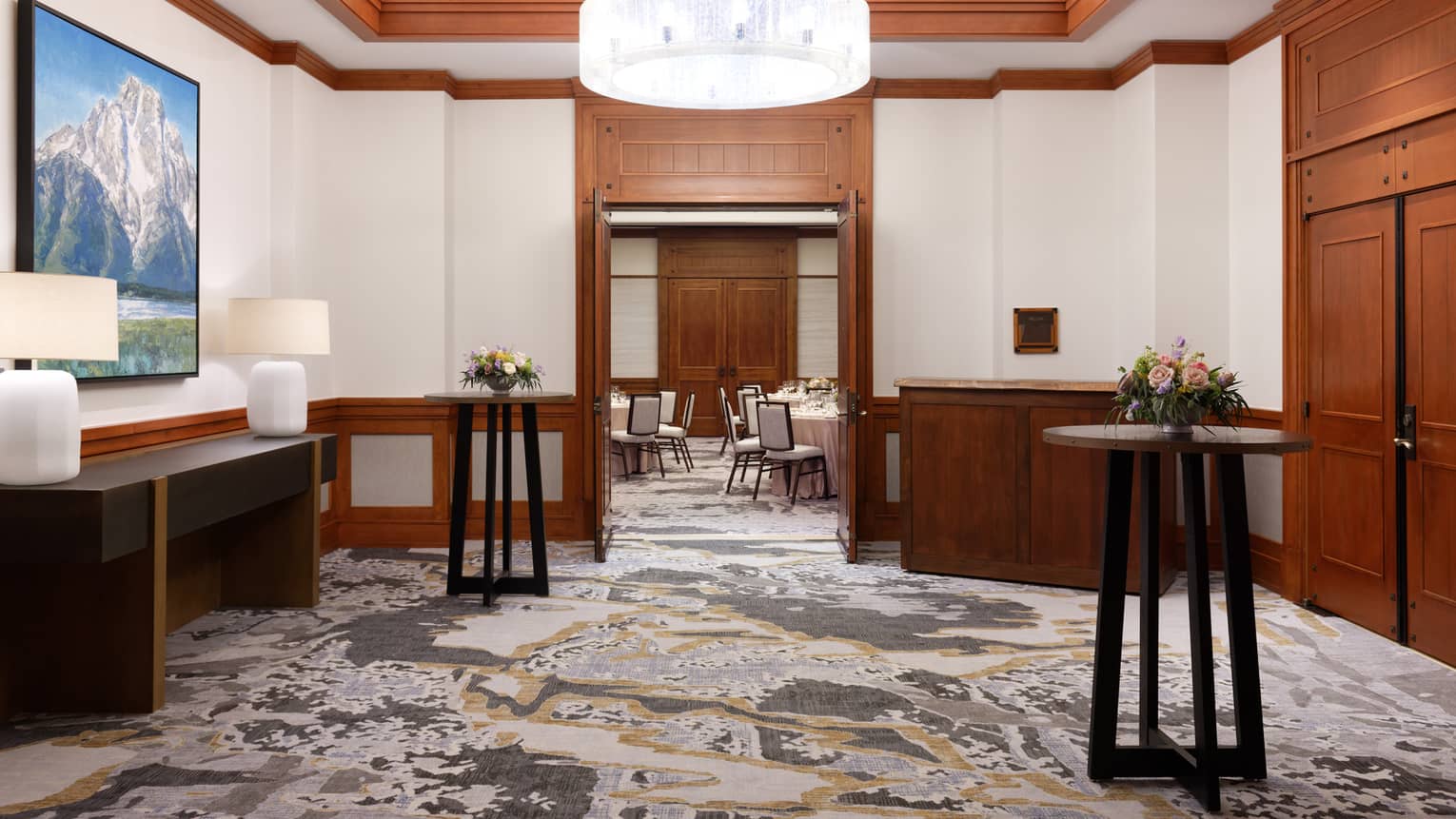 A waiting area with standing tables, lamps, and a large ceiling light.