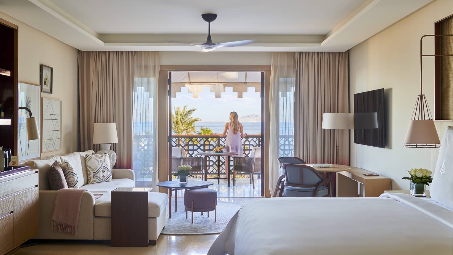 Woman stands on balcony connected to hotel room