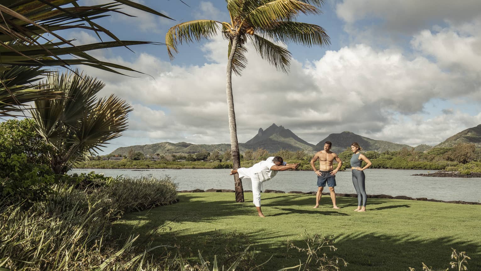 Yogi master teaches couple's yoga class beachside