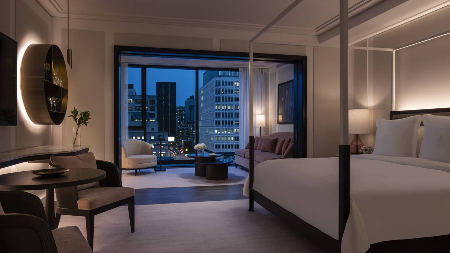 Four Seasons Executive Suite, dimly lit with four-poster modern bed and evening patio views