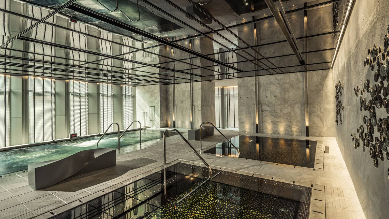 Two indoor pools, vitality pool on tile deck surrounded by marble walls, windows