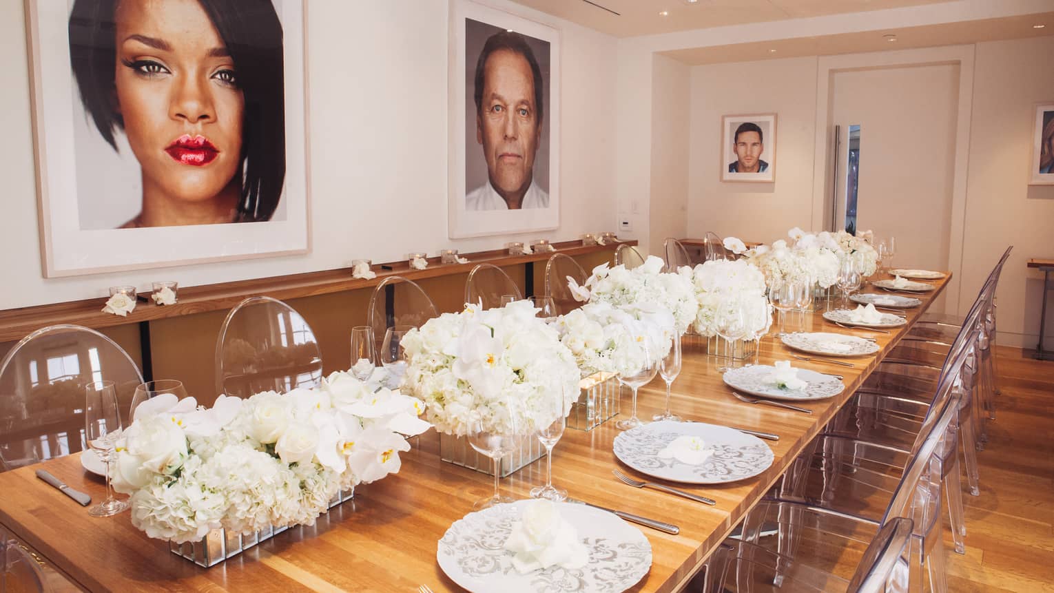 Petit Cut long wood banquet table with white roses, clear chairs, under framed prints of Hollywood stars