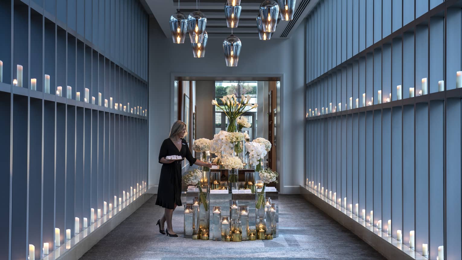 Hotel staff sets table with large flower arrangements in modern Sky Bridge